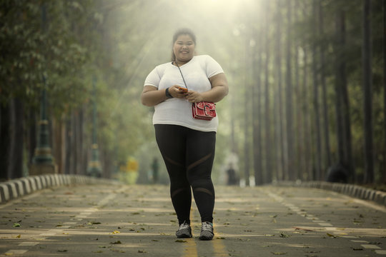 Overweight woman with smartphone in the road