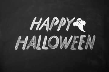 Happy Halloween made with chalk on a blackboard.