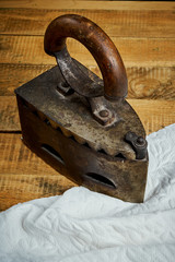 old rusty iron and a piece of cloth on a light wooden table next to a black wall