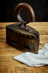 old rusty iron and a piece of cloth on a light wooden table next to a black wall