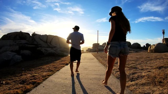 POV, couple walks on trail at sunset