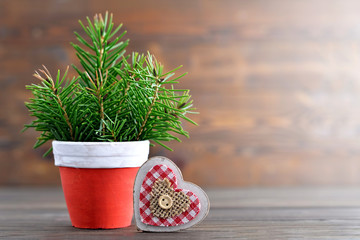 Christmas tree in the pot and vintage Christmas heart ornament on wooden background with copy space