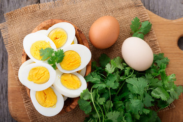 Bowl with sliced hard boiled eggs on wooden table.