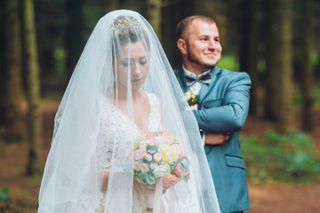 The newlyweds hug under a veil. Groom and bride against the backdrop of beautiful nature. A great...