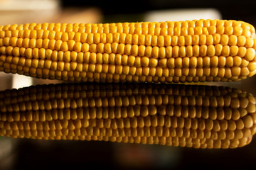 yellow sweet corn grain and a cob in the background.
