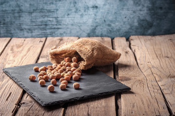 hazelnuts in rustic sack on blackboard. Wooden background