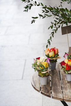 Roses and green leaves in buckets on a wooden table