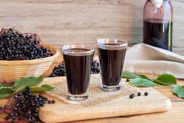 Two shots of black elder syrup with fresh elderberries