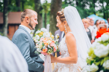 bride and groom outdoors. wedding ceremony. wedding arch. Newlyweds look to each other.