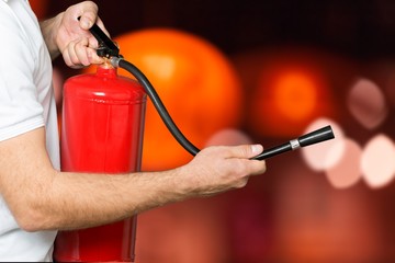 Man using fire extinguisher against grey background
