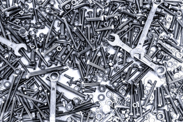 background of many different metal rivets, wrenchs, screws and bolts of silver and black color