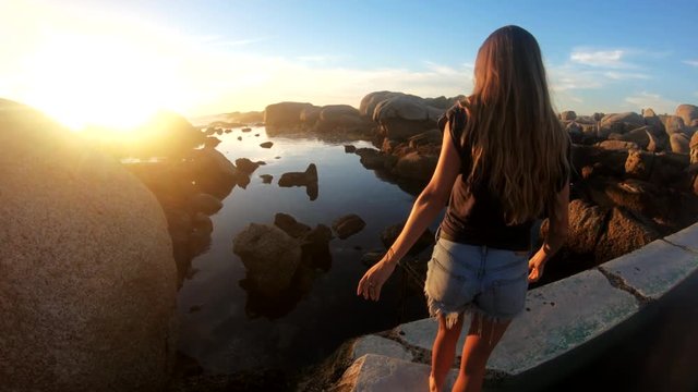 Beautiful woman walks by tidepool in Cape Town, POV