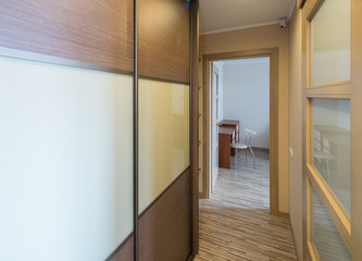 Interior of the flat. Warm tones, wooden floor. Built-in wardrobe