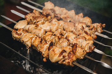 Appetizing shish kebab roasted on skewers on open air charcoal grill. Shish kebab with smoke