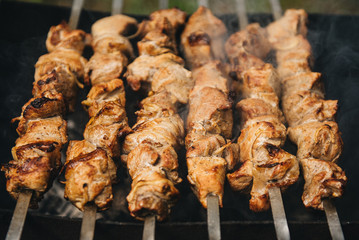 Appetizing shish kebab roasted on skewers on open air charcoal grill. Shish kebab with smoke