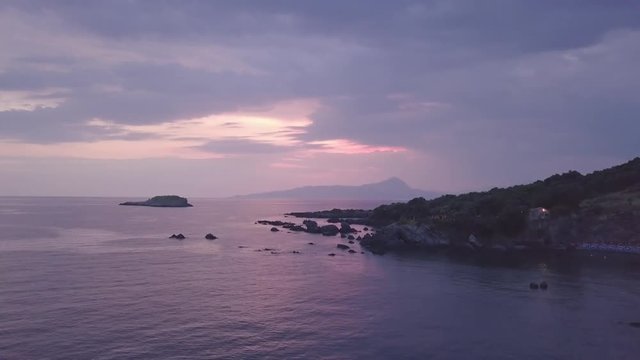 Stunning 4k sunset aerial flying through foliage over blue sea and purple clouds