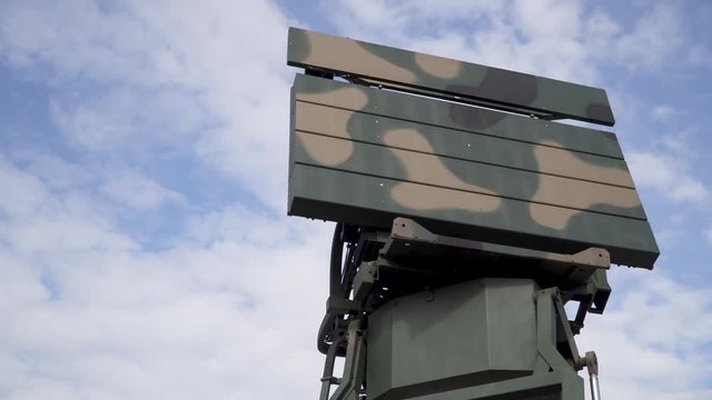Military combat radar in army paint, with clear cloudy sky in the background
(slow motion)