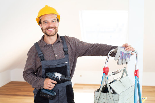 Handwerker l&auml;chelnd mit Werkzeug in einem modernen Wohnraum 