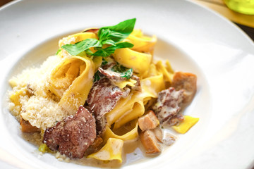 pasta tagliatelle with mushrooms in cream sauce on a white plate, macro