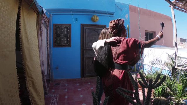 Women take photos on Morocco rooftop, POV