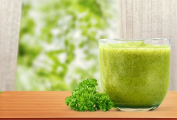 Green vegetable smoothies in glasses on wooden