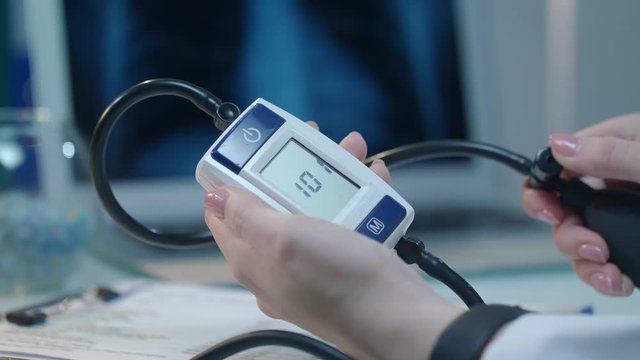 Blood pressure monitor with heart disease. Hypertension concept. Close up of female hand check blood pressure test. Medicine equipment for measure heart pressure