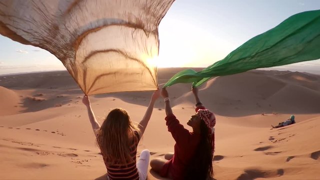 Slow motion, women hold cloth in desert