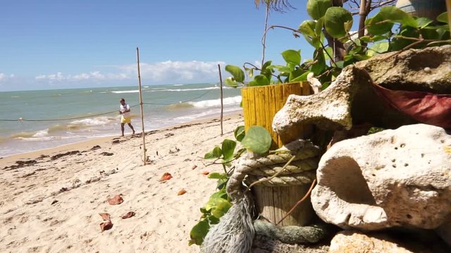 Tropical beach sunny day in Arraial D'Ajuda Bahia Brazil- fisherman&not;&yen;s stuff and a man walking