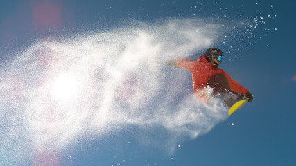 SLOW MOTION: Snowboarder jumping big air, snowflakes flying behind him in winter