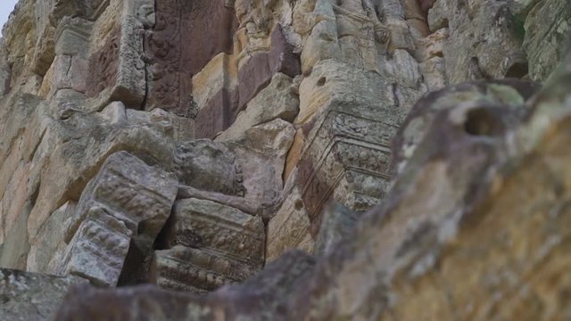 Slow pan up to a female sculpture (devata) on an ancient Khmer temple.