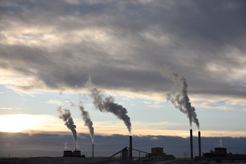 Coal-fired power plant silhouette at sunset and emissions rising from smoke stacks in Wyoming / USA.