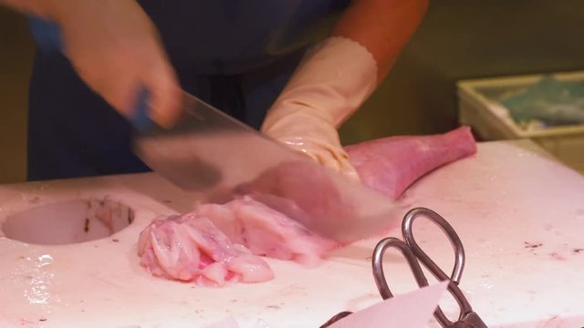 Fresh and raw fish is cutting into slices by vendor