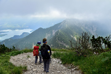 Two young children with backpacks and bandannas ready for adventure on hiking trail in the mountains