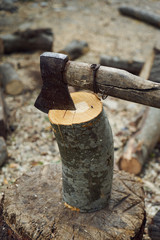 The old ax for cutting firewood sticks out in the old tree stump. A sharp ax was stuck in a round old wooden stump