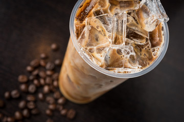 Iced coffee on dark wood table with beans