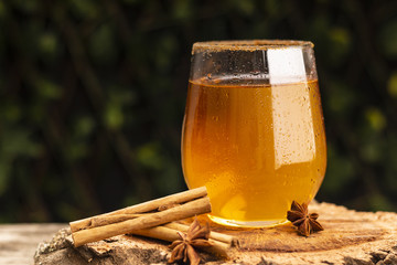 Aromatic anise lying on timber table near glass of fresh cold cider beverage