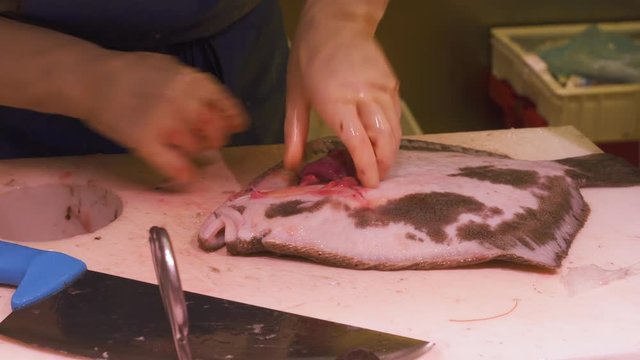 Fish vendor fillets flatfish for sale in seafood market