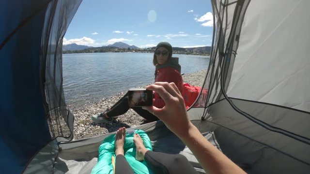 Taking photo of camper on lake shore, POV