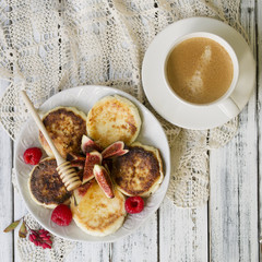 Cottage cheese pancakes with fresh figs and honey and cup ofcoffee for breakfast.