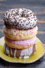 Colorful sweet glazed donuts from bakery on black wooden background close up