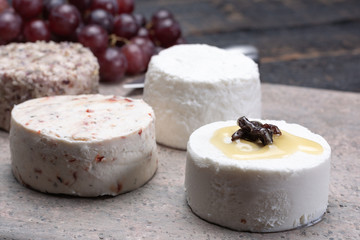 French soft cheeses, variety of different taste goat milk natural cheeses on granite plate close up sesrved as dessert