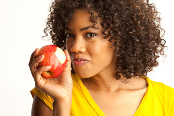 Portrait of young black woman eating fresh red apple isolated on white