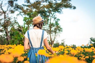 Close up portrait of happy and beautiful young woman relaxing enjoying the fresh beauty of gorgeous orange marigold flowers field in travel and holidays. Bali island.