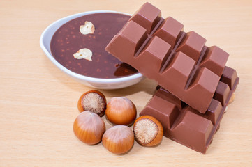 Chocolate slices and hot melted chocolate. Chocolate with hazelnuts. Nuts of hazelnuts.