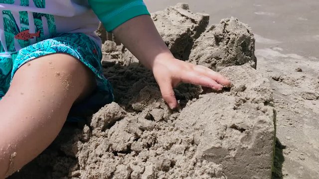 Toddler playing with sand between fingers.