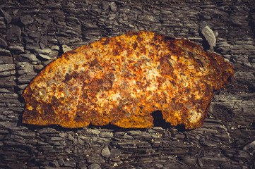 Very rusty metal on a gray cracked rock