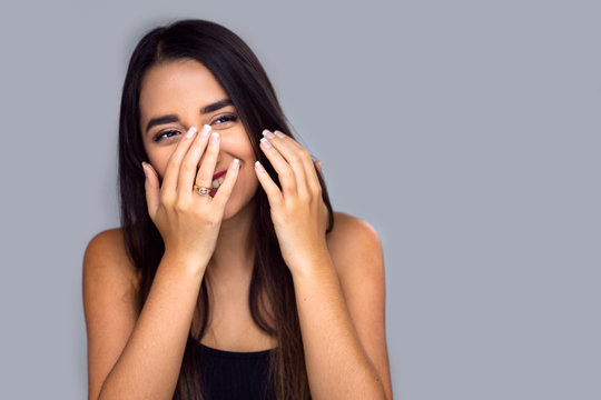 Adorable fun cute shy bashful hispanic female laughing, playful, isolated, covering face