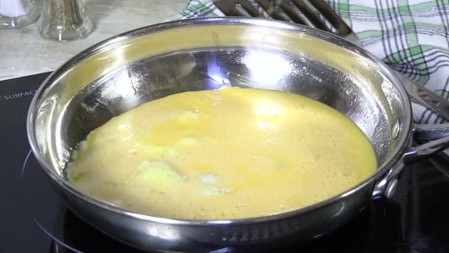 Pouring beaten egg batter into a hot frying pan
