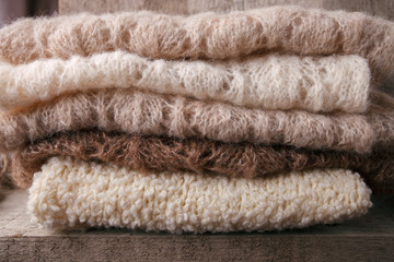 Fototapeta na wymiar Background with warm sweaters. Pile of knitted brown clothes, warm background, knitwear, space for text, Autumn winter concept. Copy Space