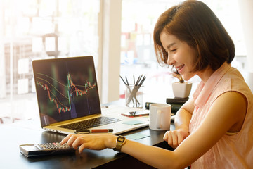 Business woman calculate finance data with laptop monitor showing a financial stock market data.